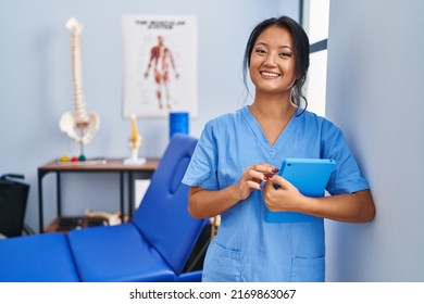 Young chinese woman wearing physiotherapist uniform using touchpad at rehab clinic - Shutterstock ID 2169863067