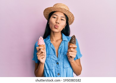 Young chinese woman wearing summer style holding ice cream looking at the camera blowing a kiss being lovely and sexy. love expression. 