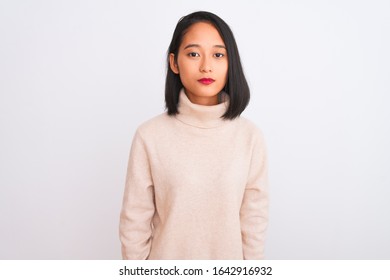 Joven china con suéter de cuello alto sobre fondo blanco aislado Relajada con expresión seria en la cara. Una mirada simple y natural a la cámara.
