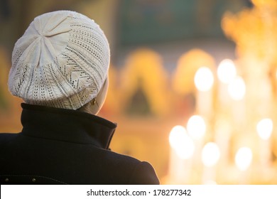 Young Christian Female Looking At Candle Flames In Church During Praying