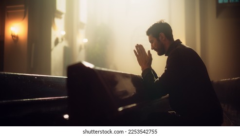 Young Christian Man Sits Piously in Majestic Church, with Folded Hands After a Cross Prayer. He Seeks Guidance From Faith and Spirituality. Religious Believer in Power and Love of God - Powered by Shutterstock