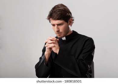 Young Christian Priest Is Praying To Cross