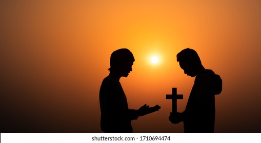 Young Christian Sharing The Gospel To Boy In Morning With Sun Light Background, Christian Silhouette Concept.