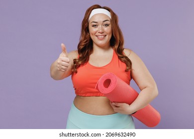 Young chubby overweight plus size big fat fit woman wearing red top warm up training hold yoga mat show thumb up like gesture isolated on purple background home gym. Workout sport motivation concept - Powered by Shutterstock