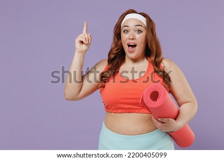 Young chubby overweight plus size big fat fit woman in red top warm up training hold yoga mat index finger up, great new idea isolated on purple background home gym Workout sport motivation concept
