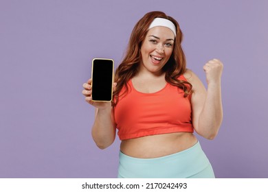 Young Chubby Plus Size Big Fat Woman In Red Top Warm Up Training Hold Yoga Mat Mobile Cell Phone Blank Screen Workspace Do Winner Gesture Isolated On Purple Background Home Gym Workout Sport Concept