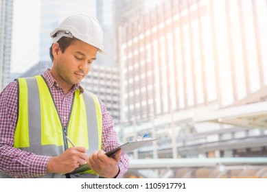 Young civil engineer reading work on clipboard for planning construction building.