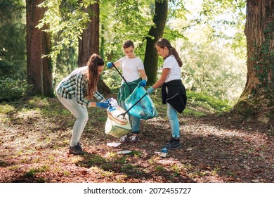 Young cleanup volunteers picking up trash in the forest, environmental care concept - Powered by Shutterstock