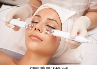 Young client of cosmetic salon having relaxing procedure on her face with special devices