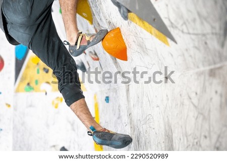 Young climber climbing on the boulder wall indoor, rear view, concept of extreme sports and bouldering