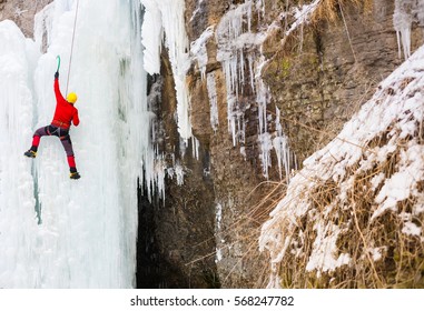 A young climber climbs on ice climbing and winter sport activities in cold weather.
