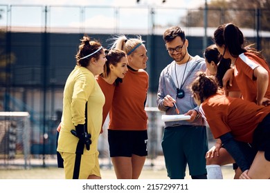 Young coach giving instructions to his female soccer team on playing field. - Powered by Shutterstock