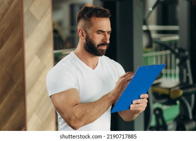 Young Coach Making A Training Plan In A Gym. Copy Space