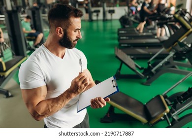 Young Coach Making A Training Plan In A Gym. Copy Space