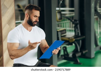 Young Coach Making A Training Plan In A Gym. Copy Space