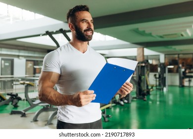 Young Coach Making A Training Plan In A Gym. Copy Space