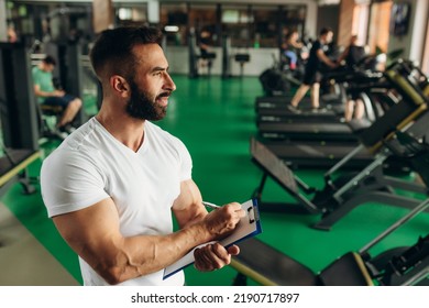 Young Coach Making A Training Plan In A Gym. Copy Space