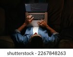 Young coder in eyeglasses is working remotely from home late at night, looking on display, typing code. Hard worker, programmer working overtime, taking work at home, has deadline. 