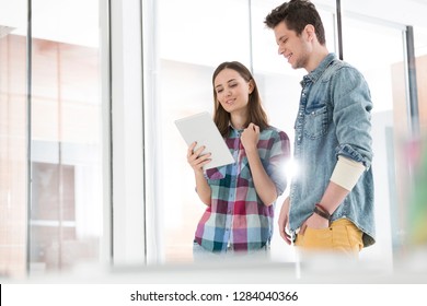 Young colleagues using tablet computer in office
