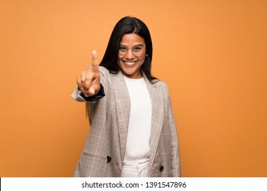 Young Colombian girl over brown wall showing and lifting a finger