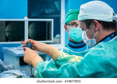 Young Concentrated Orthopedic Surgeon Team In The Operating Room Performing Open Surgery On A Human Spine After A Serious Trauma.