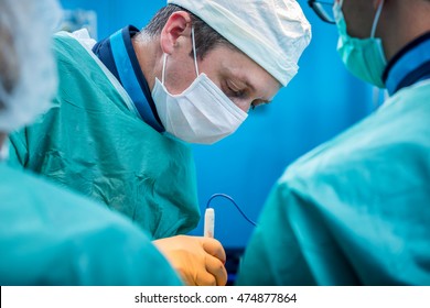 Young Concentrated Orthopedic Surgeon Team In The Operating Theater Performing Open Surgery On A Human Spine After A Serious Trauma.