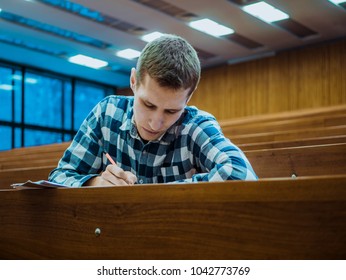 Young Concentrated Thinking Student Sitting In The Empty Big Lecture Hall On Exam