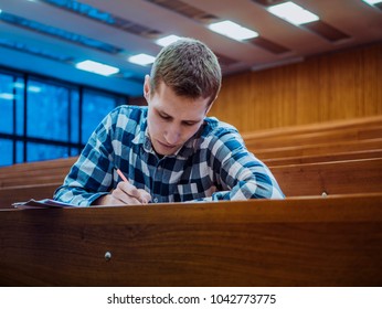 Young Concentrated Thinking Student Sitting In The Empty Big Lecture Hall On Exam