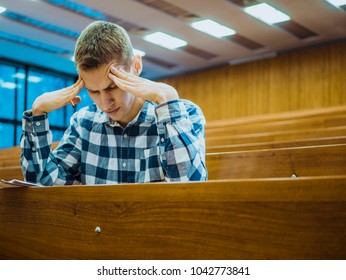 Young Concentrated Thinking Student Sitting In The Empty Big Lecture Hall On Exam