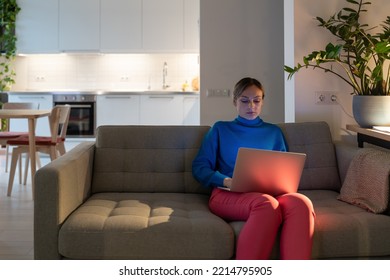 Young Concentrated Woman Using Laptop, Sit On Cozy Sofa At Home, Chatting Or Working Online. Focused Girl Writing Email, Shopping In Internet Store, Searching Information, Chatting On Social Networks.