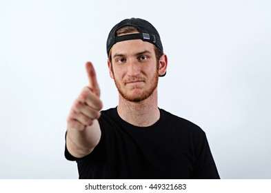 Young Confident Adult Male In Dark T-Shirt And Baseball Hat Worn Backwards Shows His Thumbs Up