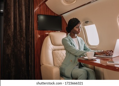 young, confident african american businesswoman working on laptop in private plane