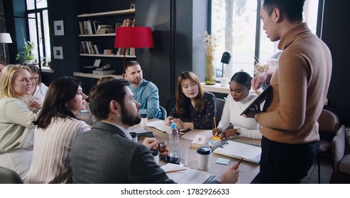 Young Confident Asian Businessman With Digital Tablet Leading Team Seminar At Loft Trendy Multiethnic Office Slow Motion