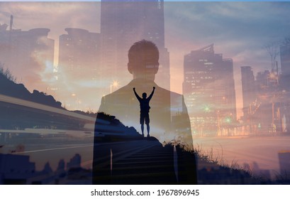 Young confident business man facing the city view. Man celebrating on a mountain top. People vision and inner strength, never giving up concept. 