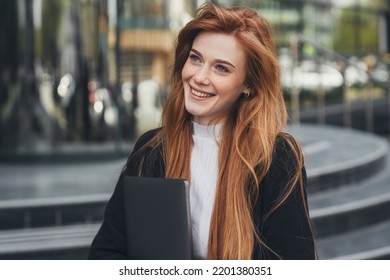 Young Confident Businesswoman In Formalwear Holding Laptop In Hands While Leaving Office Building After Hard Working Day. Job Interview. Woman Standing Outdoor