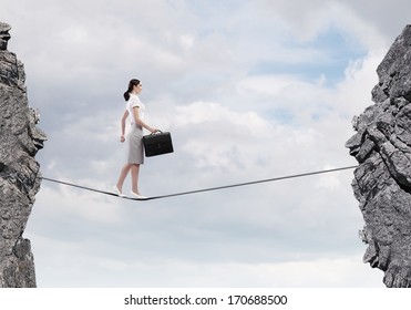 Young confident businesswoman walking on rope above gap - Shutterstock ID 170688500