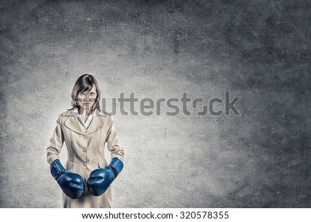 Young confident businesswoman wearing blue boxing gloves