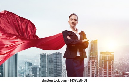 Young confident businesswoman wearing red cape against modern city background - Powered by Shutterstock