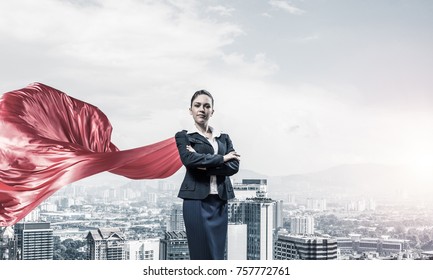 Young confident businesswoman wearing red cape against modern city background