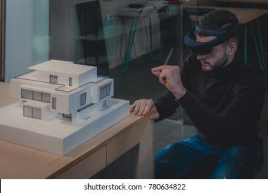 Young confident Caucasian male architect working on a private house project in the office using augmented reality glasses