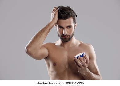 Young Confident Caucasian Man Holding Hair Gel And Touching His Ideal Hair. Handsome Bearded Guy With Naked Torso. Concept Of Hair Care. Idea Of Male Beauty. Isolated On White Background. Studio Shoot