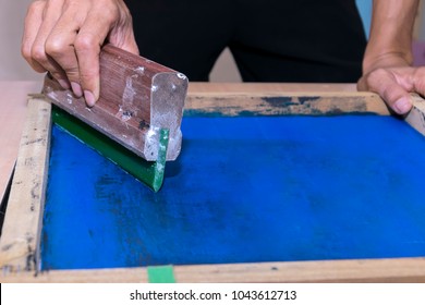 Young Confident, Experienced Male Working With Squeegee On A Small Factory,worker Man Using Printmaking Tools,screen Printing On Clothing Fabric Technique.