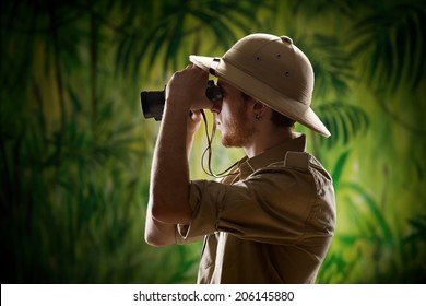 Young Confident Explorer In The Rainforest Jungle Looking Through Binoculars.