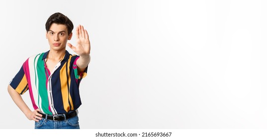 Young Confident Gay Man Saying No, Showing Stop Sign And Looking Displeased, Standing Over White Background