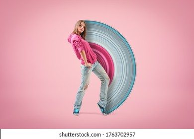 Young confident girl in pink hoodie and light blue ripped jeans standing with hand on hip looking at camera on light pink background with paintbrush visual effect. Teen fashion. Street style. - Shutterstock ID 1763702957