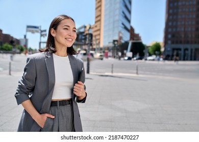 Young confident happy successful Asian business woman, professional entrepreneur, office employee wearing suit standing on city street looking in future career, thinking of success and leadership.