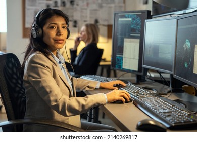 Young Confident Hispanic Female Agent Of Secret Service With Headphones Looking At Camera While Working In Office