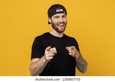 Young confident leader bearded tattooed man 20s he wears casual black t-shirt cap point index finger camera on you motivating encourage isolated on plain yellow wall background. Tattoo translate fun - Shutterstock ID 2185857753