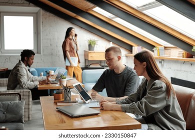 Young confident male manager with tablet making presentation of online data or project points to female colleague while sitting next to her - Shutterstock ID 2330150847