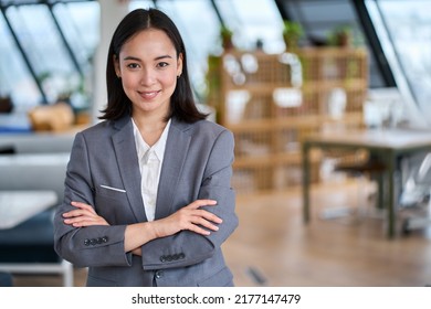 Young confident smiling Asian business woman leader, successful entrepreneur, elegant professional company executive ceo manager, wearing suit standing in office with arms crossed. Portrait